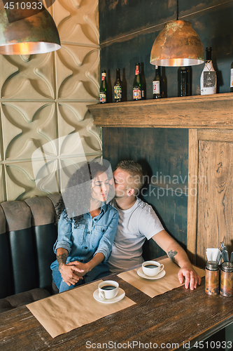 Image of Happy young couple is drinking coffee and smiling while sitting at the cafe