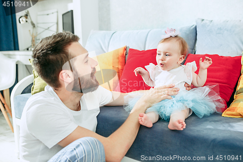 Image of Proud father holding his baby daughter at home