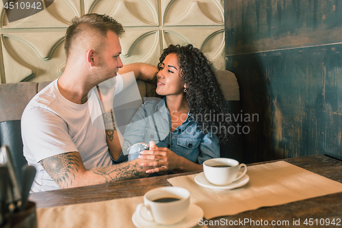 Image of Happy young couple is drinking coffee and smiling while sitting at the cafe