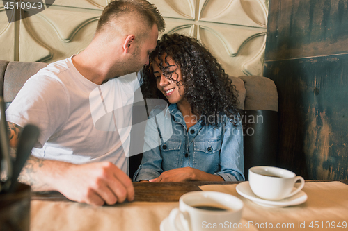 Image of Happy young couple is drinking coffee and smiling while sitting at the cafe