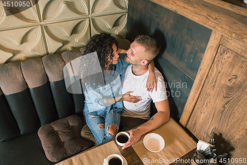 Image of Happy young couple is drinking coffee and smiling while sitting at the cafe