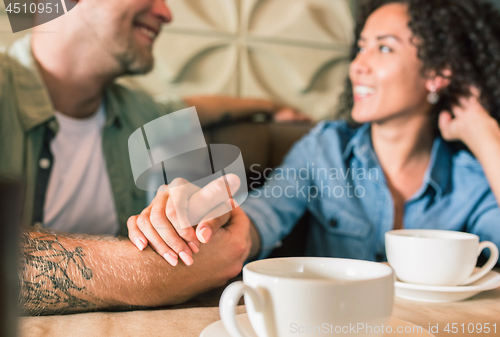 Image of Happy young couple is drinking coffee and smiling while sitting at the cafe