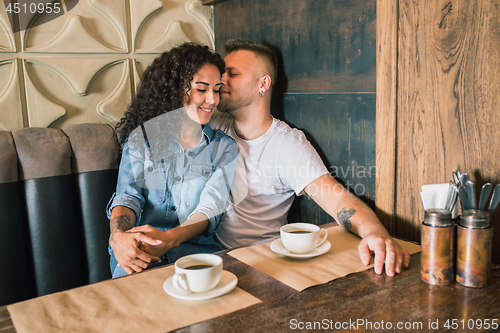 Image of Happy young couple is drinking coffee and smiling while sitting at the cafe