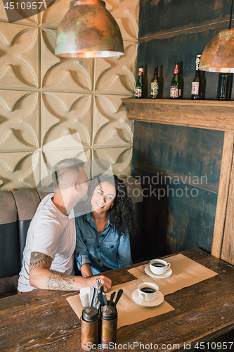 Image of Happy young couple is drinking coffee and smiling while sitting at the cafe