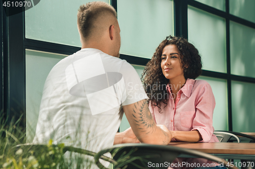 Image of Close up on a man and a woman holding hands at a wooden table