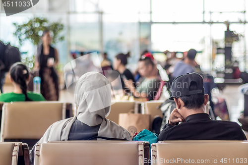 Image of Modern muslim islamic asian couple sitting and waiting for flight departure at international airport terminal