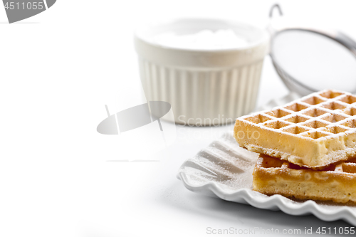 Image of Belgium waffers with sugar powder on ceramic plate and strainer 