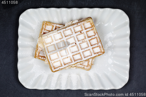 Image of Belgium waffers with sugar powder on ceramic plateon black board