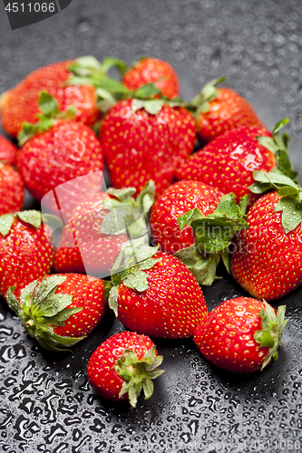Image of Fresh ripe strawberry with water drops on black.