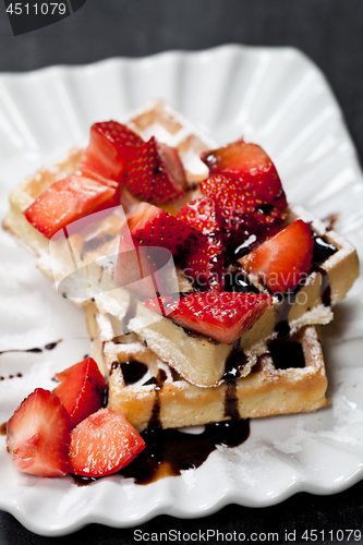 Image of Belgium waffers with sugar powder, strawberries and chocolate on