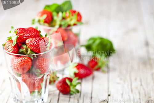 Image of Organic red strawberries in two glasses and mint leaves on rusti