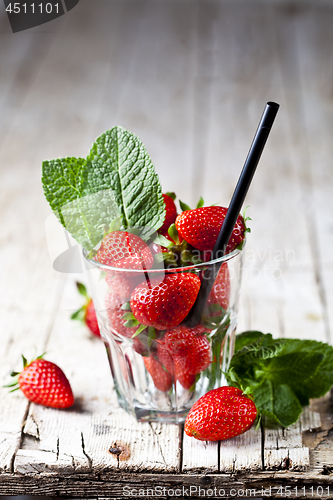 Image of Organic red strawberries glass and mint leaves on rustic wooden 