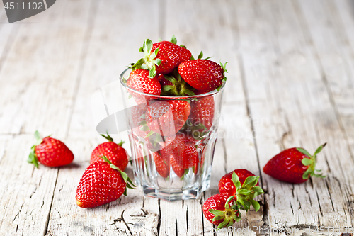 Image of Organic red strawberries in glass on rustic wooden background. 