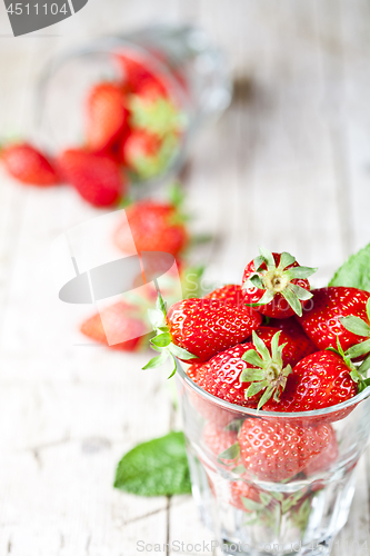 Image of Organic red strawberries in two glasses and mint leaves on rusti