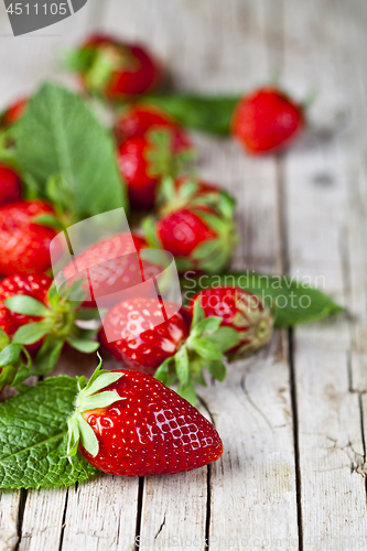 Image of Fresh red strawberries and mint leaves on rustic wooden backgrou