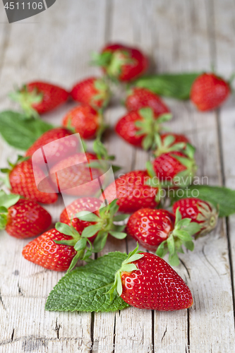 Image of Fresh red strawberries and mint leaves on rustic wooden backgrou