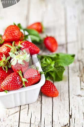 Image of Fresh red strawberries in white bowl and mint leaves on rustic w