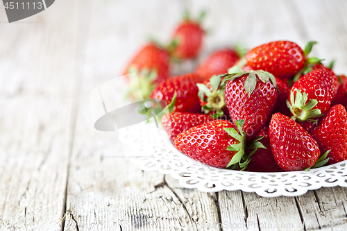 Image of Organic red strawberries on white plate on rustic wooden backgro