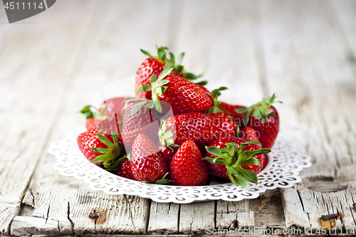 Image of Organic red strawberries on white plate on rustic wooden backgro
