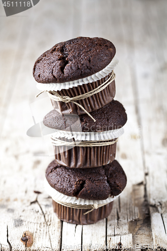 Image of Chocolate dark muffins on rustic wooden table.
