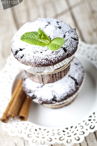 Image of Chocolate dark muffins with sugar powder, cinnamon sticks and mi