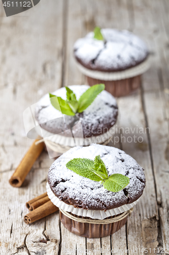 Image of Chocolate dark muffins with sugar powder, cinnamon sticks and mi