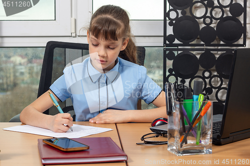 Image of An eight-year-old girl at an office table is writing an important document