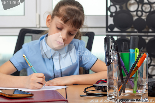 Image of Eight years old girl working in the office, focusing on office supplies