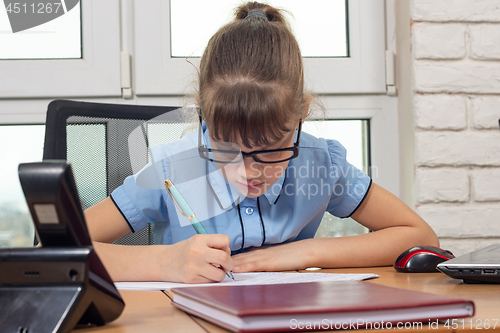 Image of An eight-year-old girl writes on a desk in an office setting