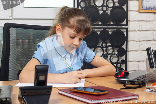 Image of An eight-year girl writes on a sheet of paper at a table in the office