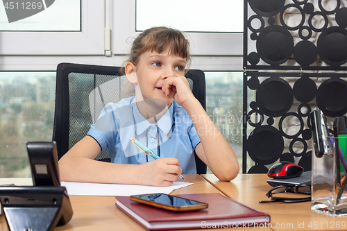 Image of Eight-year-old girl thoughtful at the table in the office