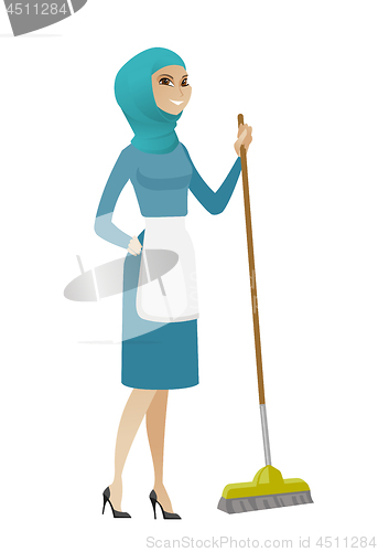 Image of Young muslim housemaid sweeping floor with a broom
