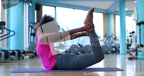 Image of back woman in a gym stretching and warming up