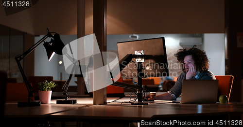 Image of man working on computer in dark office