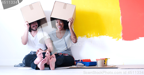 Image of young multiethnic couple playing with cardboard boxes