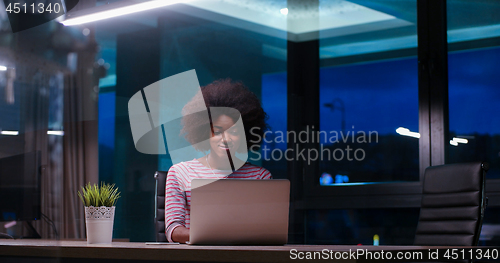 Image of black businesswoman using a laptop in night startup office
