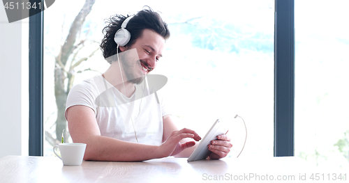 Image of young man listenig music on tablet at home