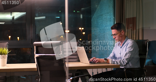 Image of man working on laptop in dark office