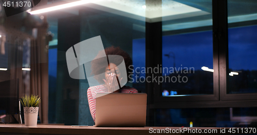 Image of black businesswoman using a laptop in night startup office