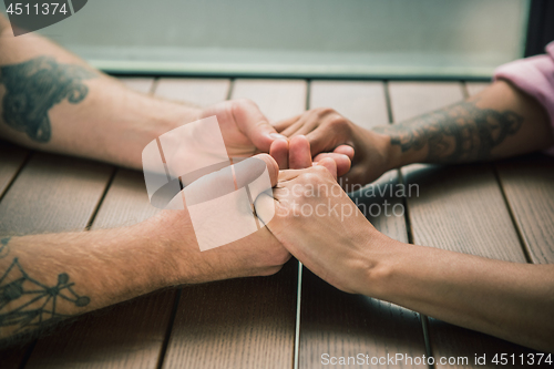 Image of Close up on a man and a woman holding hands at a wooden table