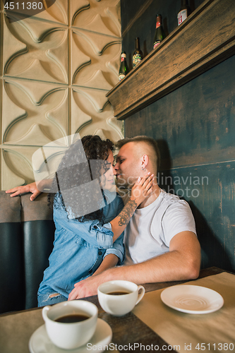 Image of Happy young couple is drinking coffee and smiling while sitting at the cafe