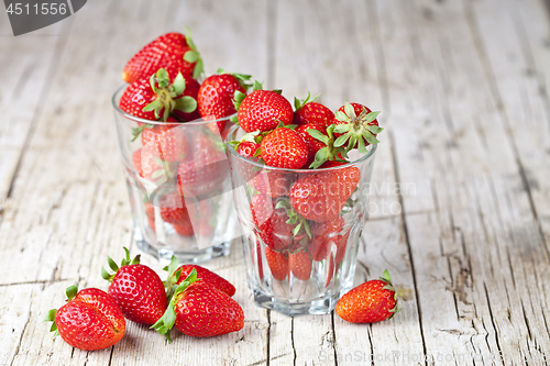 Image of Organic red strawberries in two glasses on rustic wooden backgro