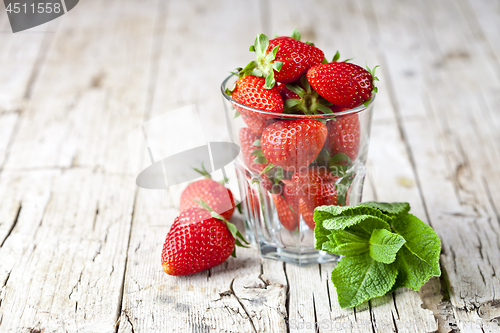 Image of Organic red strawberries glass and mint leaves on rustic wooden 