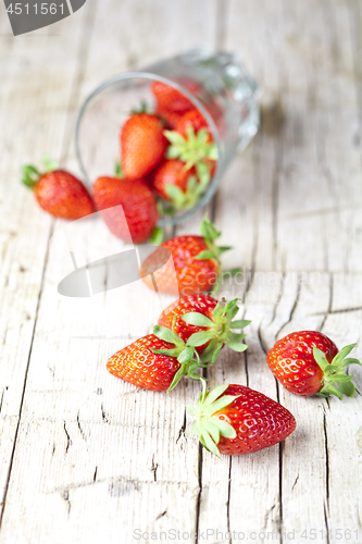 Image of Organic red strawberries in glass on rustic wooden background.