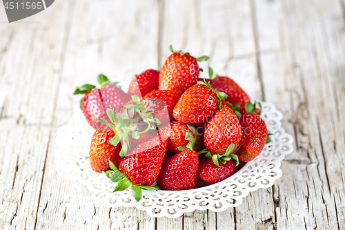 Image of Organic red strawberries on white plate on rustic wooden backgro