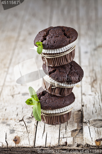 Image of Three fresh dark chocolate muffins with mint leaves.