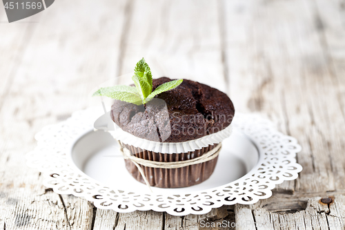 Image of Fresh dark chocolate muffin with mint leaves on white plate