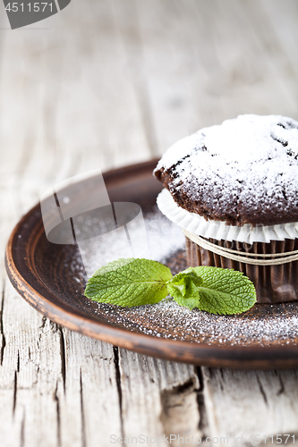 Image of Fresh chocolate dark muffin with sugar powder and mint leaf on b