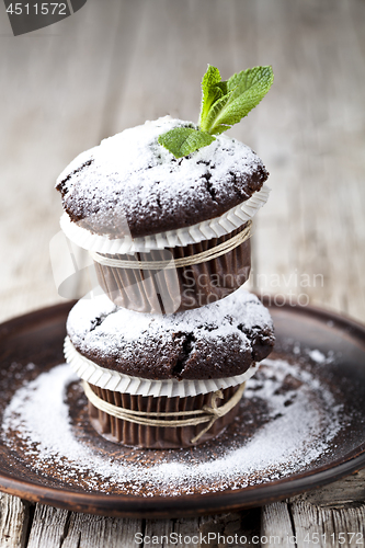 Image of Fresh chocolate dark muffins with sugar powder and mint leaf on 