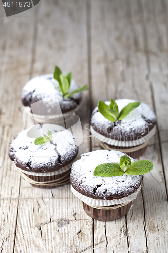 Image of Fresh chocolate dark muffins with sugar powder and mint leaf on 